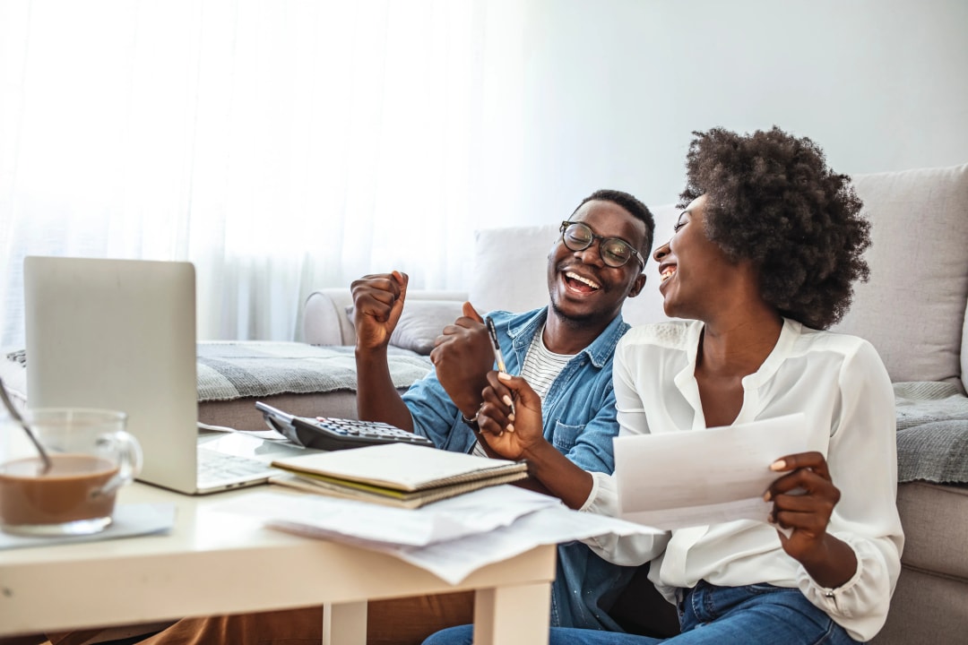 Couple assis dans leur salon utilisant une calculatrice pour planifier leur budget ou leur prêt