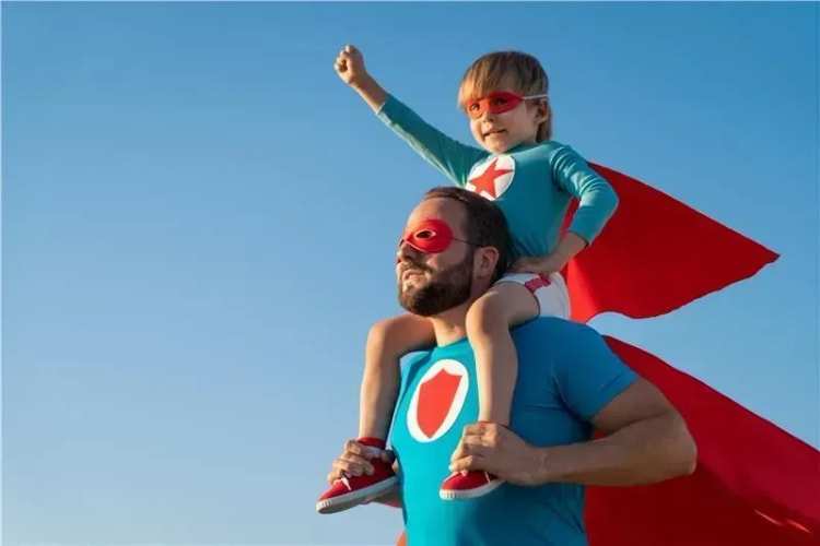 Père et fils en costume de super-héros symbolisant la protection de l'épargne familiale.