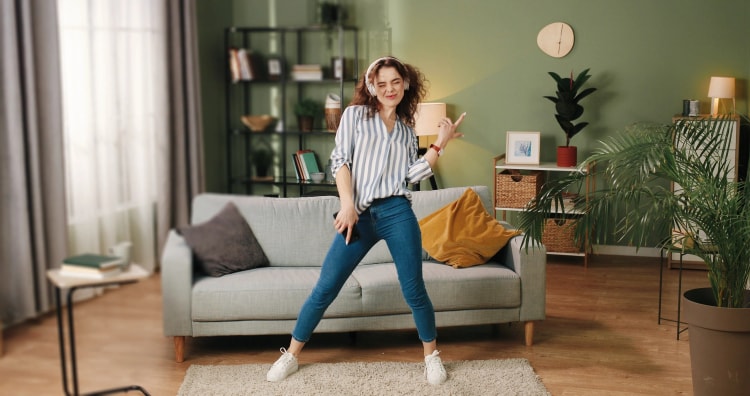 Jeune-femme-dansant-avec-des-écouteurs-dans-un-salon-moderne-et-chaleureux