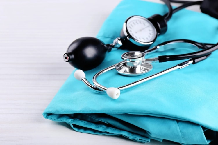 Professionnel de santé en blouse bleue avec stéthoscope, représentant les bénéficiaires de la convention AERAS pour l’assurance emprunteur