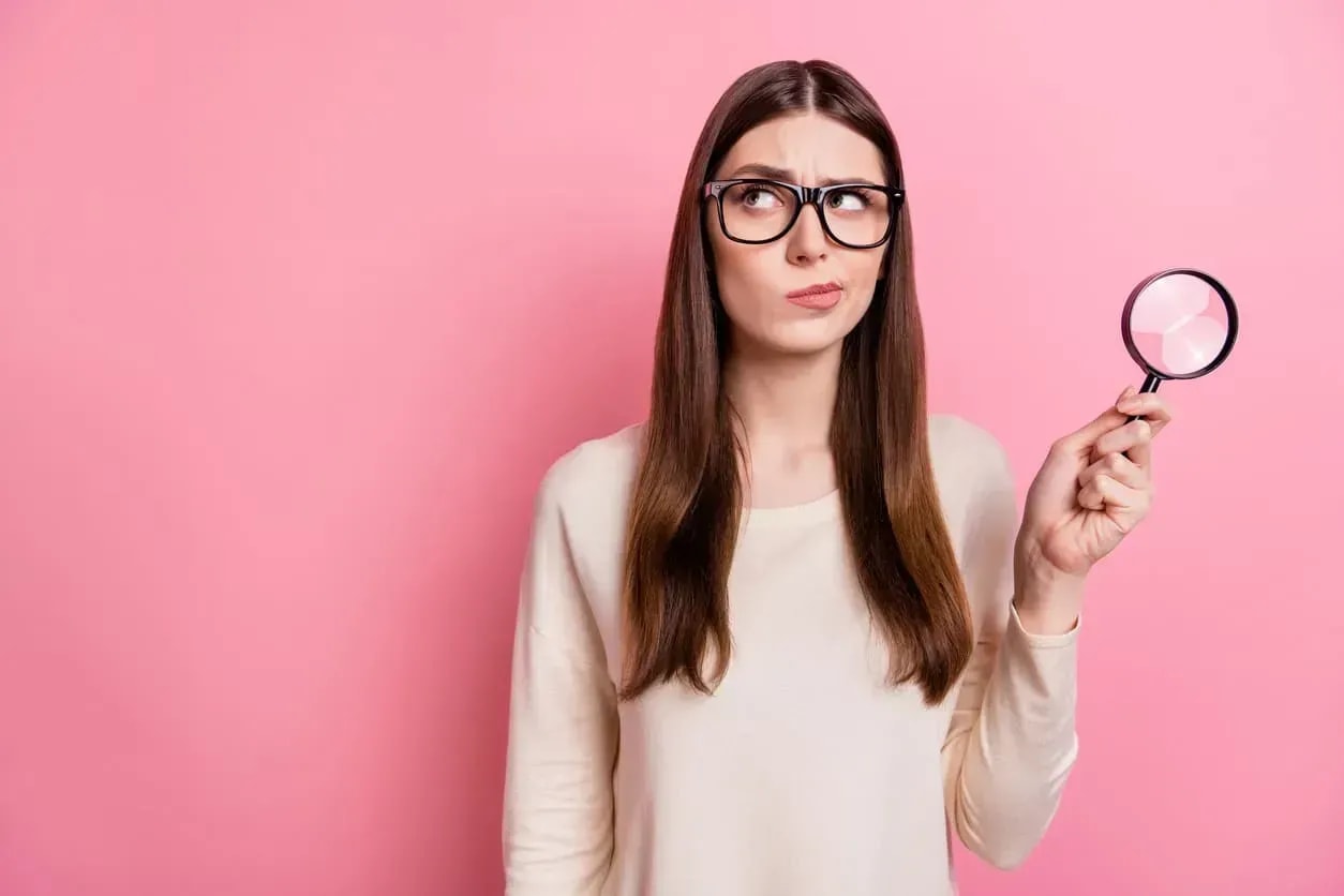 Jeune femme utilisant une loupe rose pour examiner les détails d’un crédit à la consommation