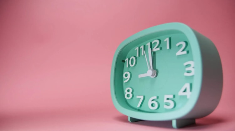 reveil-moderne-de-couleur-bleu-cyan-pose-dans-un-fond-rose