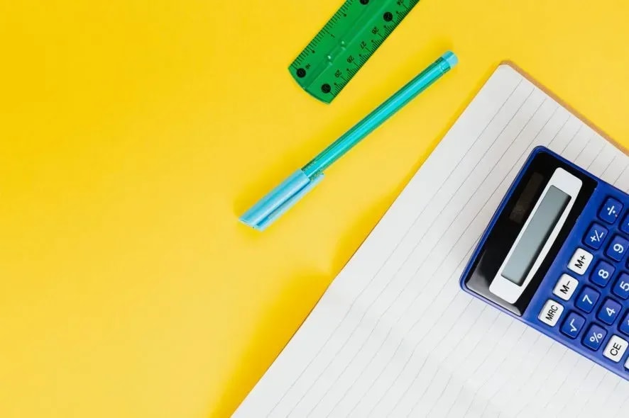 Matériels scolaire calculatrice-poser-sur-un-cahier-ouvert-a-cote-d-un-stylo-et-d-une-regle-derriere-un-fond-jaune
